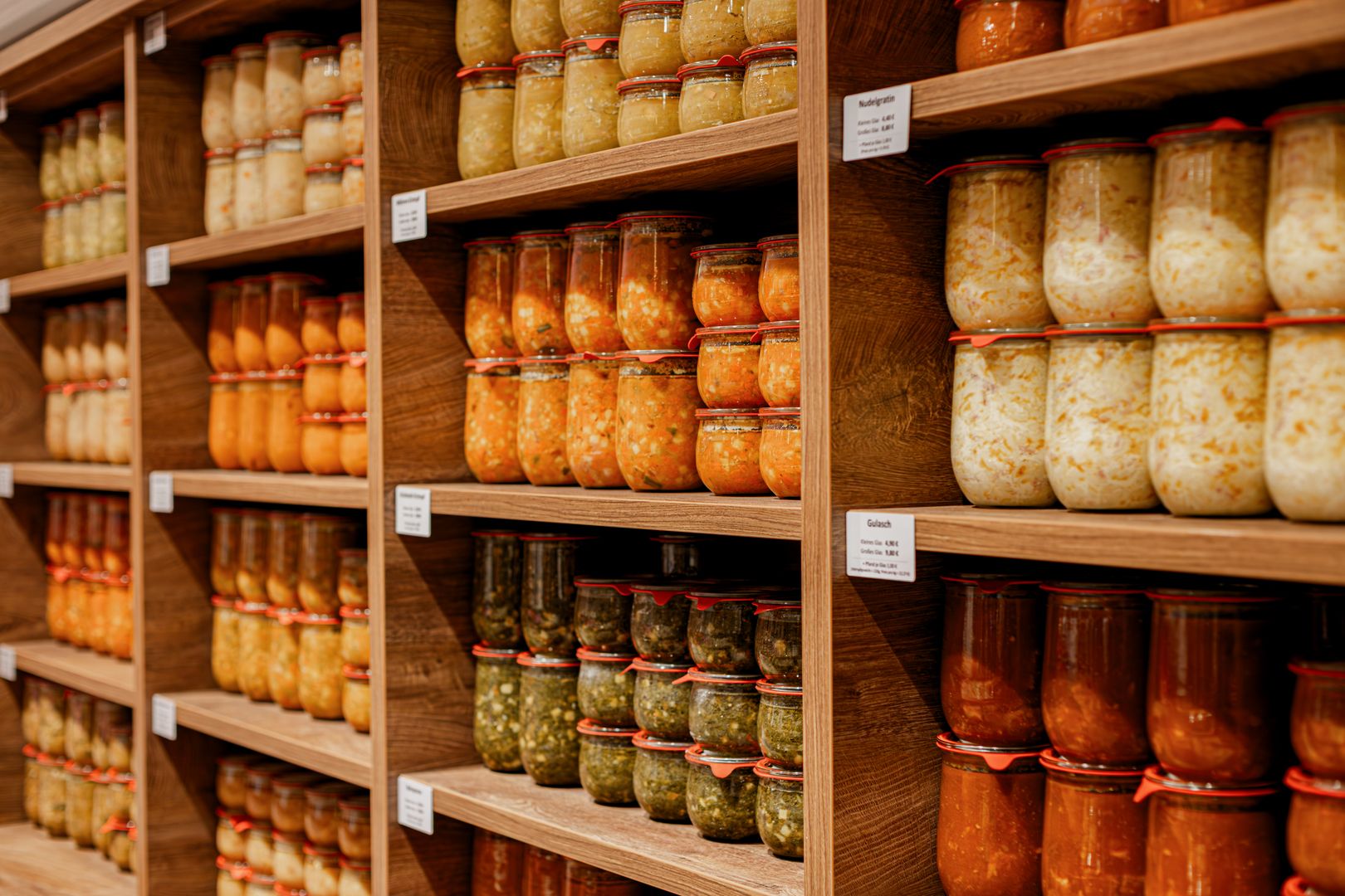 Regal mit mehreren Reihen von Einmachgläsern, gefüllt mit verschiedenen eingelegten Lebensmitteln